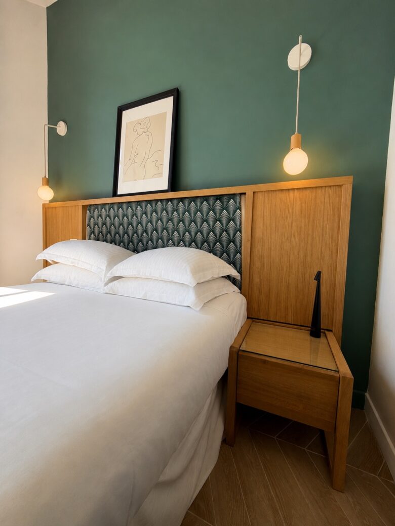 Chambre au mur vert avec tête de lit capitonnée et appliques en laiton, Hôtel Bellevue Marseille